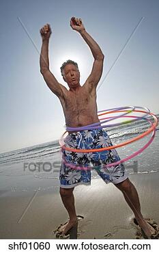Stock Photography - mature man with 
many hula hoops 
at the beach. 
fotosearch - search 
stock photos, 
pictures, images, 
and photo clipart