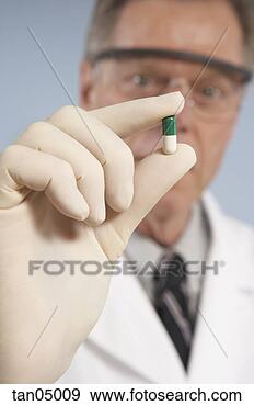 Stock Photograph - scientist holding 
capsule. fotosearch 
- search stock 
photos, pictures, 
images, and photo 
clipart