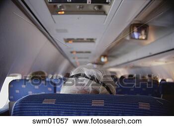 Picture - senior man using 
headphones on 
airplane. fotosearch 
- search stock 
photos, pictures, 
images, and photo 
clipart