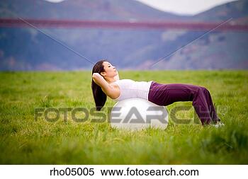 Stock Image - woman exercising 
outdoors with 
exercise ball 
on grass. fotosearch 
- search stock 
photos, pictures, 
images, and photo 
clipart