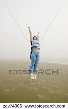 Stock Photo - woman jumping 
on beach in fog. 
fotosearch - search 
stock photos, 
pictures, images, 
and photo clipart