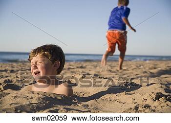 Stock Photograph - young boy buried 
in sand. fotosearch 
- search stock 
photos, pictures, 
images, and photo 
clipart
