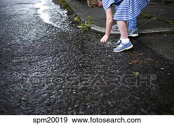 Stock Photograph - young boy picking 
things up off 
wet street. fotosearch 
- search stock 
photos, pictures, 
images, and photo 
clipart