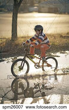 Picture - young boy riding 
bicycle through 
puddle. fotosearch 
- search stock 
photos, pictures, 
images, and photo 
clipart
