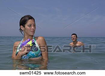 Stock Image - young couple playing 
with squirt guns 
in ocean. fotosearch 
- search stock 
photos, pictures, 
images, and photo 
clipart