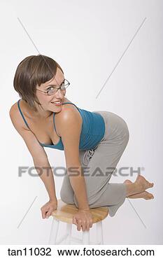 Stock Photo - young woman kneeling 
on stool. fotosearch 
- search stock 
photos, pictures, 
images, and photo 
clipart