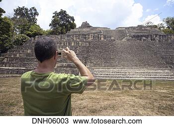 Stock Photo - man taking photo 
of caana structure, 
caracol, belize. 
fotosearch - search 
stock photos, 
pictures, images, 
and photo clipart
