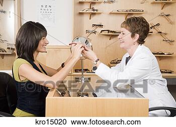 Stock Photography - female optician 
giving eyeglasses 
to woman. fotosearch 
- search stock 
photos, pictures, 
images, and photo 
clipart