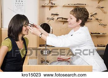 Stock Photo - female optician 
putting eyeglasses 
on woman. fotosearch 
- search stock 
photos, pictures, 
images, and photo 
clipart