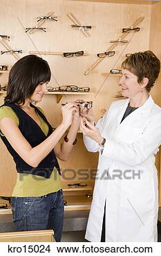 Stock Photo - female optician 
showing eyeglasses 
to woman. fotosearch 
- search stock 
photos, pictures, 
images, and photo 
clipart