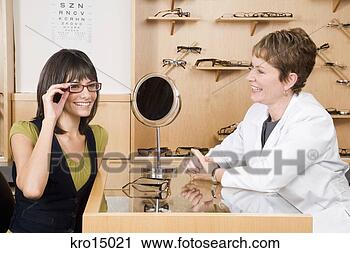 Stock Photography - woman trying on 
eyeglasses in 
optician’s office. 
fotosearch - search 
stock photos, 
pictures, images, 
and photo clipart