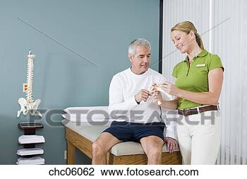 Stock Photo - physical therapist 
and patient looking 
at bone model. 
fotosearch - search 
stock photos, 
pictures, images, 
and photo clipart