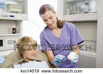 Stock Photograph - female dentist 
showing patient 
how to brush. 
fotosearch - search 
stock photos, 
pictures, images, 
and photo clipart