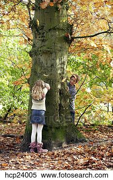 Stock Image - girl and boy playing 
hide-and-seek 
in the woods. 
fotosearch - search 
stock photos, 
pictures, images, 
and photo clipart