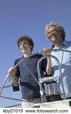 Stock Photograph - father teaching 
son to steer boat. 
fotosearch - search 
stock photos, 
pictures, images, 
and photo clipart