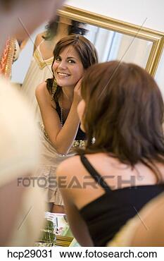 Stock Photography - young woman putting 
on earrings in 
the mirror. fotosearch 
- search stock 
photos, pictures, 
images, and photo 
clipart