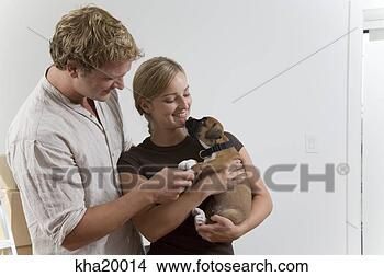 Banco de Imagem - par,  segurando, 
 filhote cachorro. 
fotosearch - busca 
de fotos, imagens 
e clipart