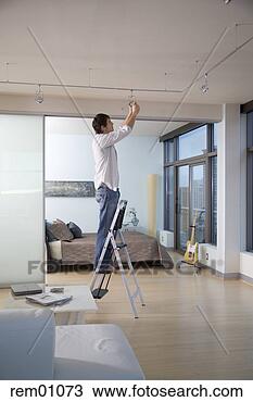 Stock Photo - young adult man 
changing light 
bulb. fotosearch 
- search stock 
photos, pictures, 
images, and photo 
clipart