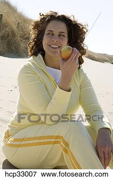 Foto - mulher,  comer, 
 maçã,  praia. 
fotosearch - busca 
de fotos, imagens 
e clipart