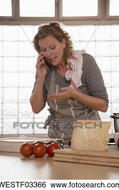 Stock Photo - mature woman in 
kitchen, using 
mobile phone. 
fotosearch - search 
stock photos, 
pictures, images, 
and photo clipart