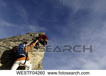 Stock Photography - young couple climbing 
on mountain peak, 
man helping woman, 
rear view. fotosearch 
- search stock 
photos, pictures, 
images, and photo 
clipart