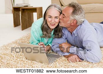 Stock Photo - mature couple 
lying on carpet 
with laptop, man 
kissing woman. 
fotosearch - search 
stock photos, 
pictures, images, 
and photo clipart