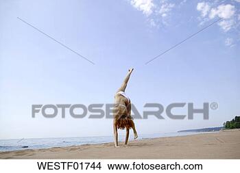 Banco de Imagem - jovem,  mulher, 
 fazer,  handstand, 
 praia. fotosearch 
- busca de fotos, 
imagens e clipart