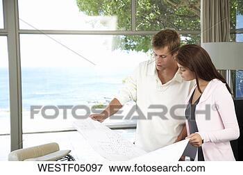 Picture - couple in living 
room with construction 
plans. fotosearch 
- search stock 
photos, pictures, 
images, and photo 
clipart