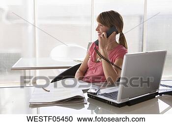 Arquivo de Fotografias - mulher,  escrivaninha, 
 usando,  telefone. 
fotosearch - busca 
de fotos, imagens 
e clipart