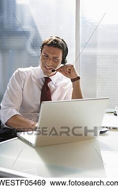 Arquivo Fotográficos - negócio,  sentando, 
 escrivaninha, 
 usando,  cabeça, 
 jogo. fotosearch 
- busca de fotos, 
imagens e clipart