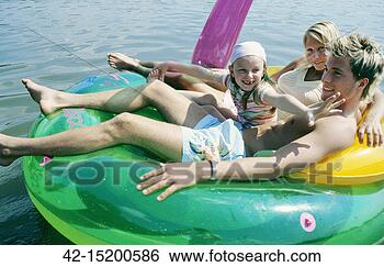 Stock Photo - happy family of 
three on water 
toy in water. 
fotosearch - search 
stock photos, 
pictures, images, 
and photo clipart