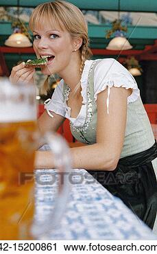 Stock Photography - blonde woman in 
dirndl eating 
sandwich at table. 
fotosearch - search 
stock photos, 
pictures, images, 
and photo clipart