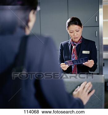 Stock Photo - airline check-in 
attendant reading 
a ticket. fotosearch 
- search stock 
photos, pictures, 
images, and photo 
clipart