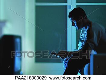 Stock Photograph - man sitting and 
watching television, 
holding remote 
control, side 
view. fotosearch 
- search stock 
photos, pictures, 
images, and photo 
clipart