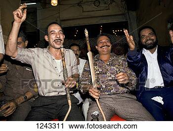 Stock Photography - a group of men  smoking shisha  pipes and cheering  musicians in a  cafe. fotosearch  - search stock  photos, pictures,  images, and photo  clipart