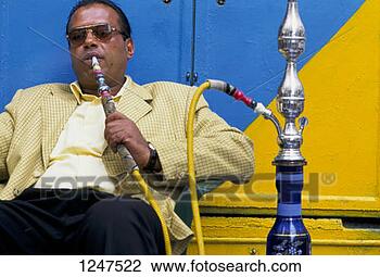 Stock Photo - a middle-aged  man sitting smoking  a hookah in tripoli,  libya. fotosearch  - search stock  photos, pictures,  images, and photo  clipart