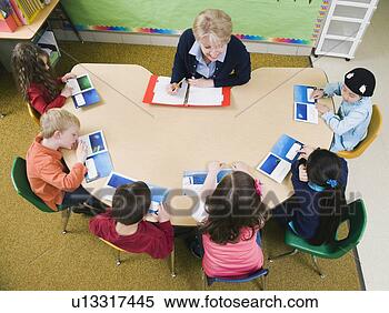 Stock Image - kindergarten students sitting at table with their teacher. fotosearch - search stock photos, pictures, wall murals, images, and photo clipart